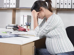 Беременная девушка грустит в офисе